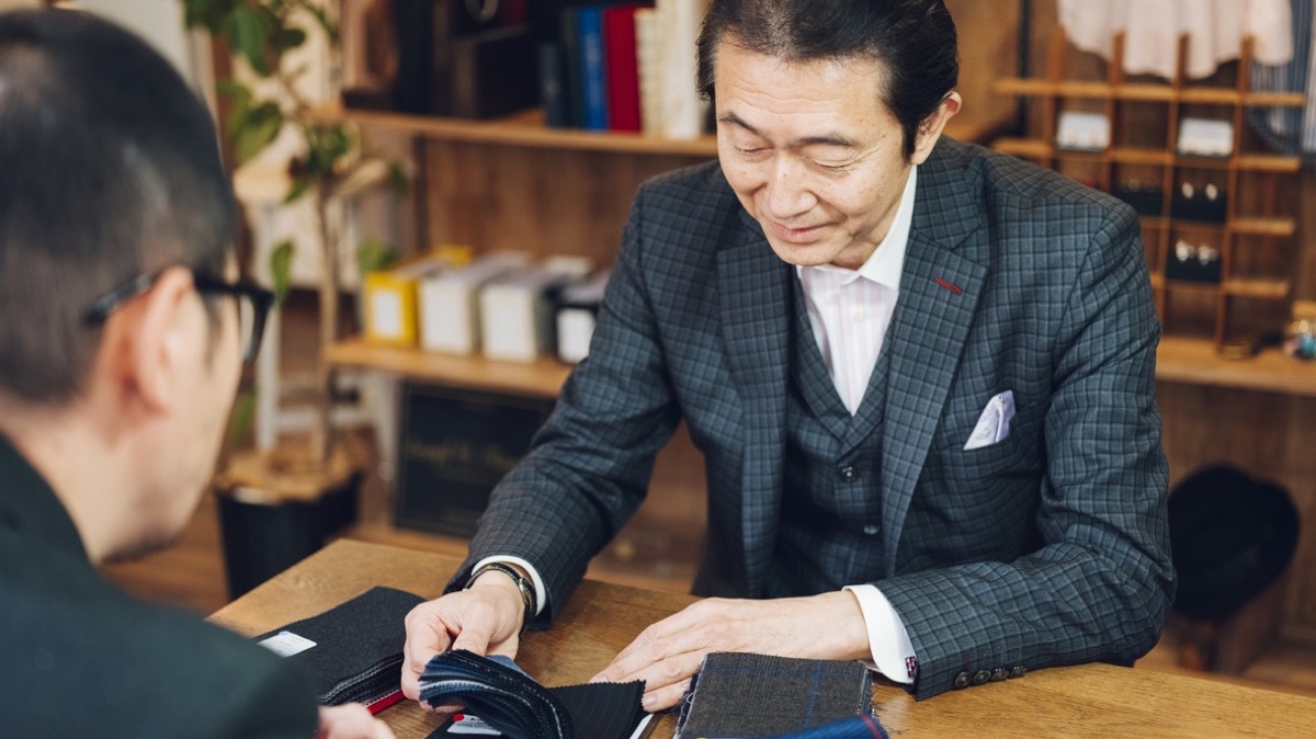 オーダースーツ店で生地を選ぶ接客の様子