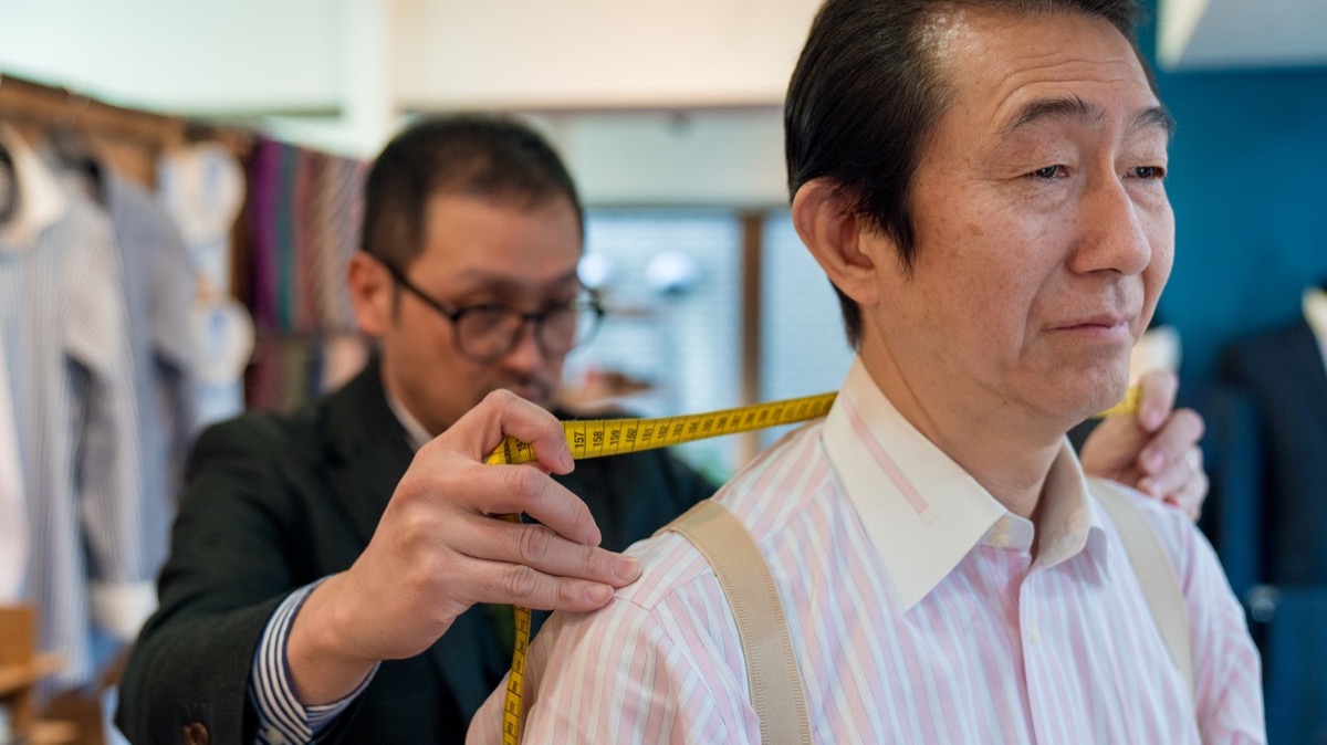 テーラーがメジャーでお客様の肩幅を測る様子
