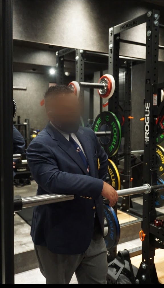 仕上がったブレザー姿でトレーニングジムに立つお客様